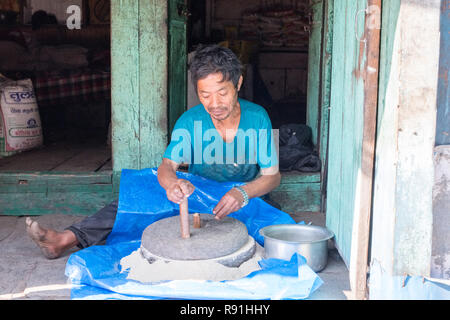 Uomo nepalese macinazione di farina con una mano macina azionata Foto Stock