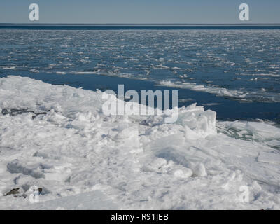 Neve e frastagliati cumuli di ghiaccio galleggiante in acqua aperta e si accumulano lungo la riva del Lago Superiore nel nord del Minnesota negli Stati Uniti. Foto Stock