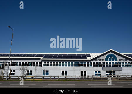 Pannelli fotovoltaici solari montati sul tetto di edifici commerciali con cielo blu chiaro, a Bury lancashire uk Foto Stock