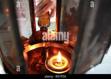 Buddisti di rendere merito,l'olio riempire in una lampada per l'illuminazione e per l'uso nell'incenso. Mezzi per rendere la vita senza intoppi. Messa a fuoco selettiva. Foto Stock