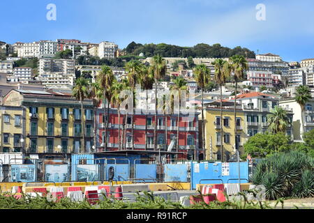 Lo stile mediterraneo appartamento case densamente costruire sulla collina ripida con alcune alte palme davanti in città italiana. Foto Stock