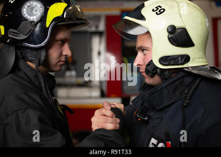 Foto di due vigili del fuoco che indossa caschi sventolando la loro stretta di mano Foto Stock