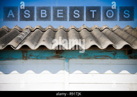 Pericolo tetto in amianto. Il termine amianto scritto con lettere la cui figura ricorda la forma di particelle di amianto. Foto Stock