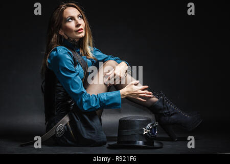A piena lunghezza steampunk donna retrò con cilindro di studio shot grunge sfondo scuro Foto Stock