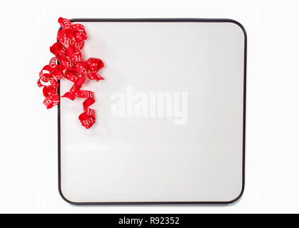 Curly red Natale nastro su carta bianca lavagna cancellabile isolati su sfondo bianco Foto Stock