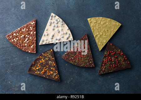 Forma di triangolo cioccolato fette di pizza con diversi tipi di condimenti su sfondo blu, vista dall'alto Foto Stock