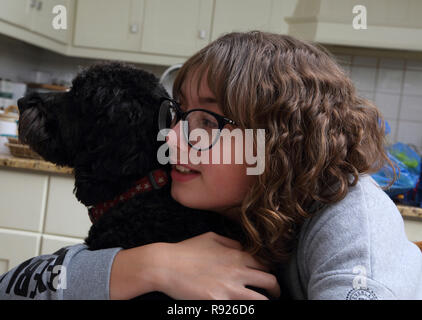 Ragazza di dodici anni abbracciando un cane Cockapoo Surrey in Inghilterra Foto Stock