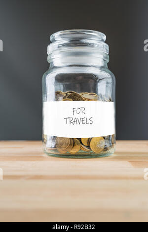 Vaso con monete in oro su legno naturale dello sfondo. Risparmiare denaro per viaggi concetto astratto. Foto Stock
