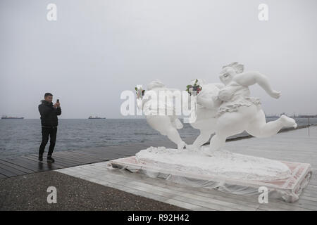 Salonicco, Grecia. Xviii Dicembre, 2018. Un uomo prende le foto di una scultura dell'artista cinese Xu Hongfei presso il porto della città di Salonicco, Grecia, a Dic. 18, 2018. Artista cinese Xu Hongfei, presidente della scultura di Guangzhou Academy, presentato 15 delle sue sculture di figure femminili per il porto della città di Salonicco in Grecia settentrionale, come parte di un tour mondiale della sua esposizione. Credito: Dimitris Tosidis/Xinhua/Alamy Live News Foto Stock