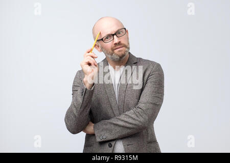 Uomo europeo è pensando a qualcosa di graffiare il suo volto con matita Foto Stock