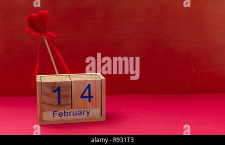 Il giorno di San Valentino. Calendario di cubi di legno con 14 febbraio testo e velluto rosso a cuore, contro lo sfondo di colore rosso, spazio di copia Foto Stock