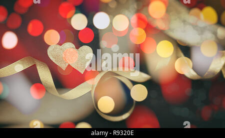 Il giorno di San Valentino. Vista superiore del rosso e del golden cuori con nastro di raso contro lo sfondo nero, bokeh, carta da parati. Foto Stock