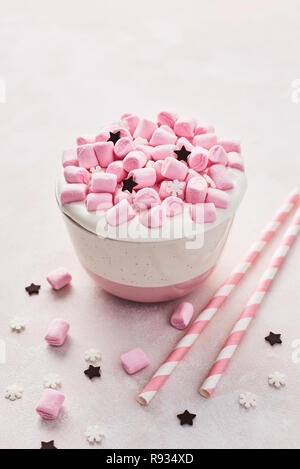 Cioccolata calda o di cacao con panna montata e rosa marshmallow candy decorate con fiocchi di neve di zucchero e cioccolato di stelle con strisce rosa cannucce su un Foto Stock