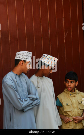 Giovani uomini Omani indossando il tradizionale Jalabiya e un Kuma cap. Foto Stock