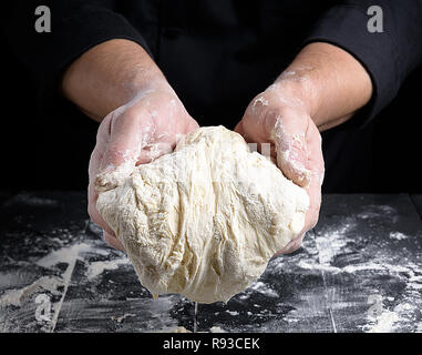 Gli uomini con le mani in mano tenendo una palla bianca di pasta lievitata al di sopra della tabella Foto Stock