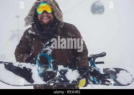 Ritratto di uomo barbuto occhiali da sci snowboard di contenimento Foto Stock