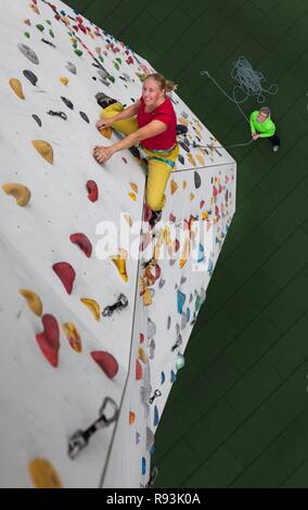 Arrampicata, donna salite davanti a escalation artificiale facility, prospettiva dall'alto verso il basso che fissano la persona, Germania Foto Stock