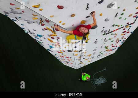 Arrampicata, donna salite davanti a escalation artificiale facility, prospettiva dall'alto verso il basso che fissano la persona, Germania Foto Stock