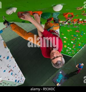 Arrampicata, donna salite davanti a escalation artificiale facility, prospettiva dall'alto verso il basso che fissano la persona, Germania Foto Stock