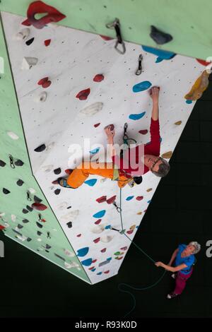 Arrampicata, donna salite davanti a escalation artificiale facility, prospettiva dall'alto verso il basso che fissano la persona, Germania Foto Stock