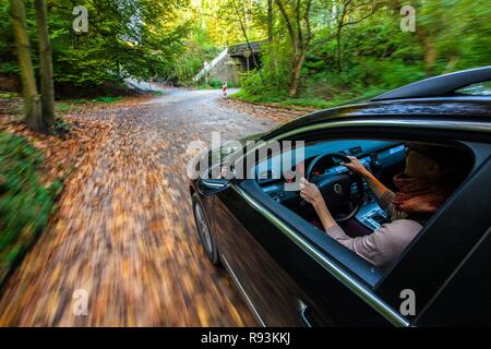 Auto guidando su una strada coperta con le foglie in autunno, pericolose condizioni di guida, pericolo di incidente Foto Stock