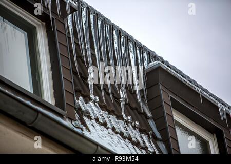 Grandi ghiaccioli appesi al cornicione di una casa, segno di una mal isolato dal calore del tetto, Essen, Nord Reno-Westfalia, Germania Foto Stock