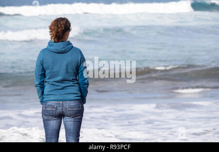 Vista posteriore della donna che guarda al mare Foto Stock