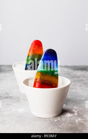 Rainbow gelati ghiaccioli su sfondo grigio Foto Stock