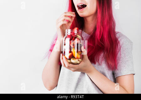 Giovane donna con capelli rosa è in possesso di un barattolo di vetro con vari frutti e bacche. Concetto dei pasti per andare Foto Stock