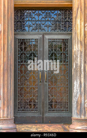 Ornato porta in ferro incorniciato da verticale colonne scanalate Foto Stock