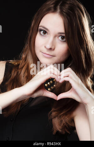 L'amore il giorno di san valentino del concetto. Donna teen ragazza facendo formare forma di cuore amore simbolo con le sue mani su nero Foto Stock