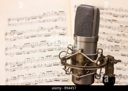 Microfono da studio con un punteggio musicale foglio in background Foto Stock