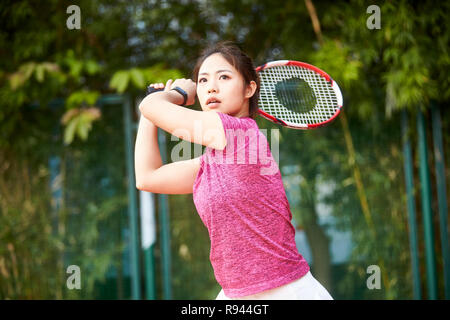 Giovane donna asiatica femmina giocatore di tennis di colpire la palla con diretti Foto Stock