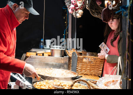 Stall Trader serve un cliente con cibo caldo al mercato di Natale di Harrogate., North Yorkshire, Inghilterra, Regno Unito. Foto Stock