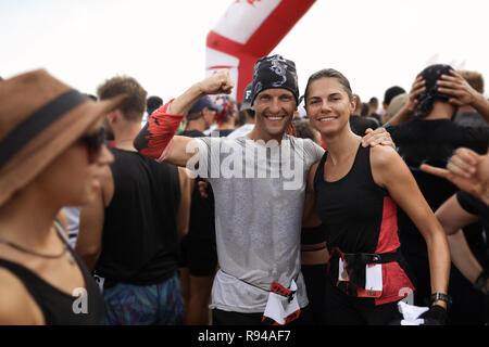 Due persone in amore, felice e sorridente tenendo una parte in una gara. Uomo in grigio di t-shirt e dreadlocks sotto la bandana che mostra il suo bicipite. La donna in nero Foto Stock