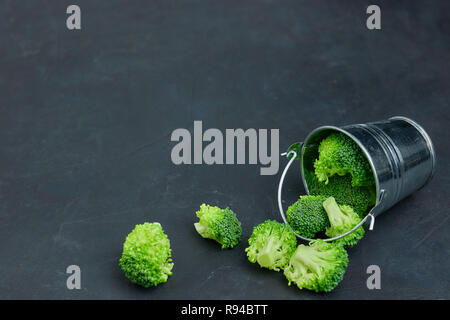 Placer broccoli verdi segmenti da un piccolo cucchiaio. Mangiare sano pattern su sfondo scuro. Spazio Copia vista dall'alto. Cibo vegetariano. Foto Stock