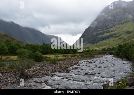 Il COE del fiume che scorre attraverso la valle di Glencoe Mountain Range nelle Highlands Scozzesi. Prese a piovere e Nuvoloso Giorno di agosto. Foto Stock