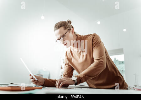 Alto giovani designer bello in eyewear guardando pensieroso Foto Stock