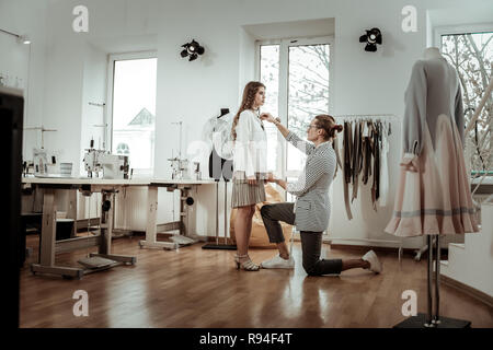 Piuttosto dai capelli scuri nel modello di un mantello beige lavora in uno showroom Foto Stock