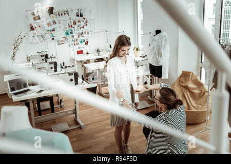 Trasmissione via IR di incredibile ragazza dai capelli scuri in un mantello beige feeling positivo Foto Stock