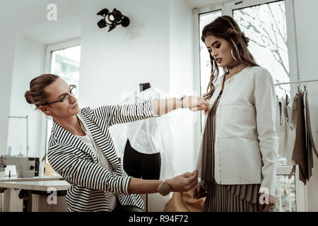 Bello con i capelli lunghi designer di moda in occhiali in grado di rendere le misurazioni Foto Stock