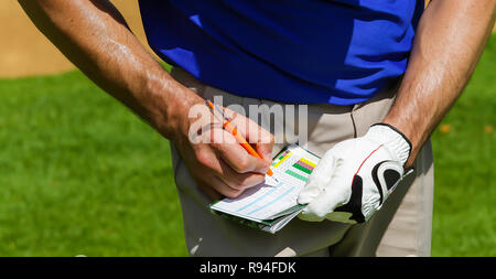 Sudati golfista tenere il punteggio sulla scorecard in una giornata di sole Foto Stock