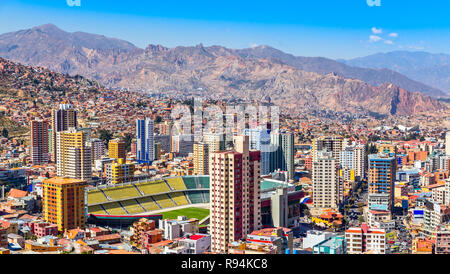 Nuestra Senora de la Paz colorata città centro città con grattacieli, stadio di calcio e un sacco di vita case sparse sulle colline con Andes mount Foto Stock