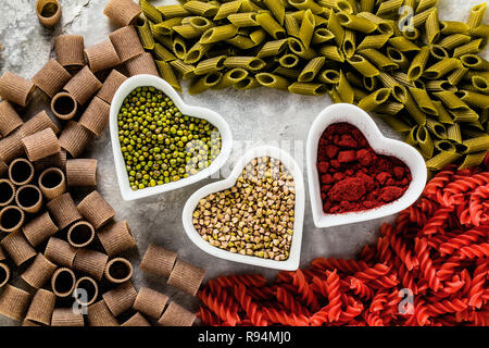 Multicolor pasta aglutinica con ingredienti in ciotole in forma di cuori da cui essa è fatta su un tavolo di pietra Foto Stock