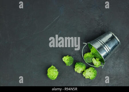 Placer broccoli verdi segmenti da un piccolo cucchiaio. Mangiare sano pattern su sfondo scuro. Spazio Copia vista dall'alto. Cibo vegetariano. Foto Stock