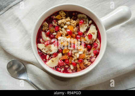 Acai Smoothie ciotola e rabboccato con melograno, banane, flaxseeds, semi di cedro, albicocca secca e granola. Acai colazione frullato superfoods ciotola Foto Stock