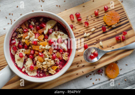 Acai Smoothie ciotola e rabboccato con melograno, banane, flaxseeds, semi di cedro, albicocca secca e granola. Acai colazione frullato superfoods ciotola. Overh Foto Stock