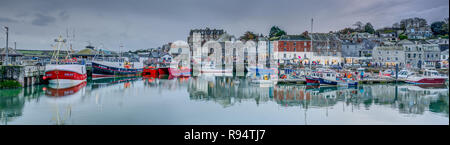 Una panoramica del tardo pomeriggio luce in inverno a Padstow Harbour, Cornwall, Inghilterra. Una varietà di colorati posti barca, edifici e una riflessione di acqua Foto Stock