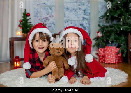 Bambini carino, un ragazzo e una ragazza, divertendosi a Natale, Natale decorazione intorno a loro Foto Stock