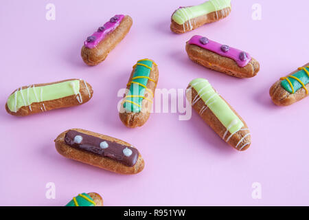 Primo piano della sparsi decorate eclairs francese dessert sulla tavola di rosa Foto Stock